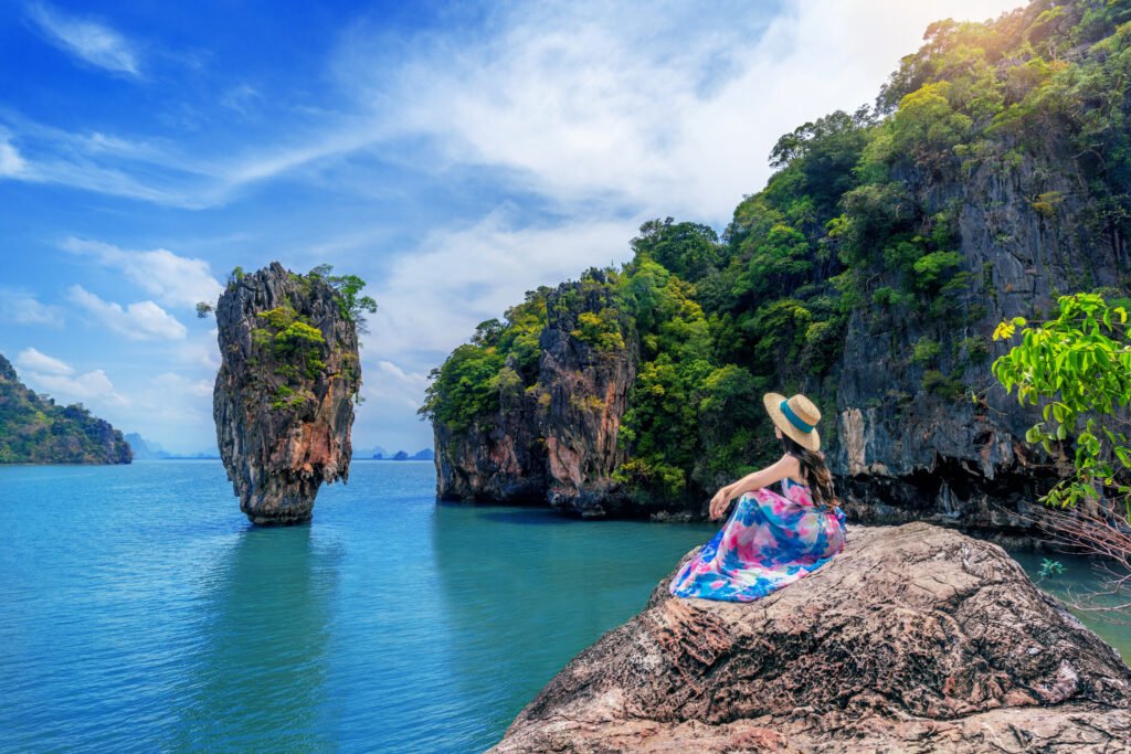 Beautiful girl sitting on the rock at James Bond island in Phang Beautiful girl sitting on the rock at James Bond island in Phang